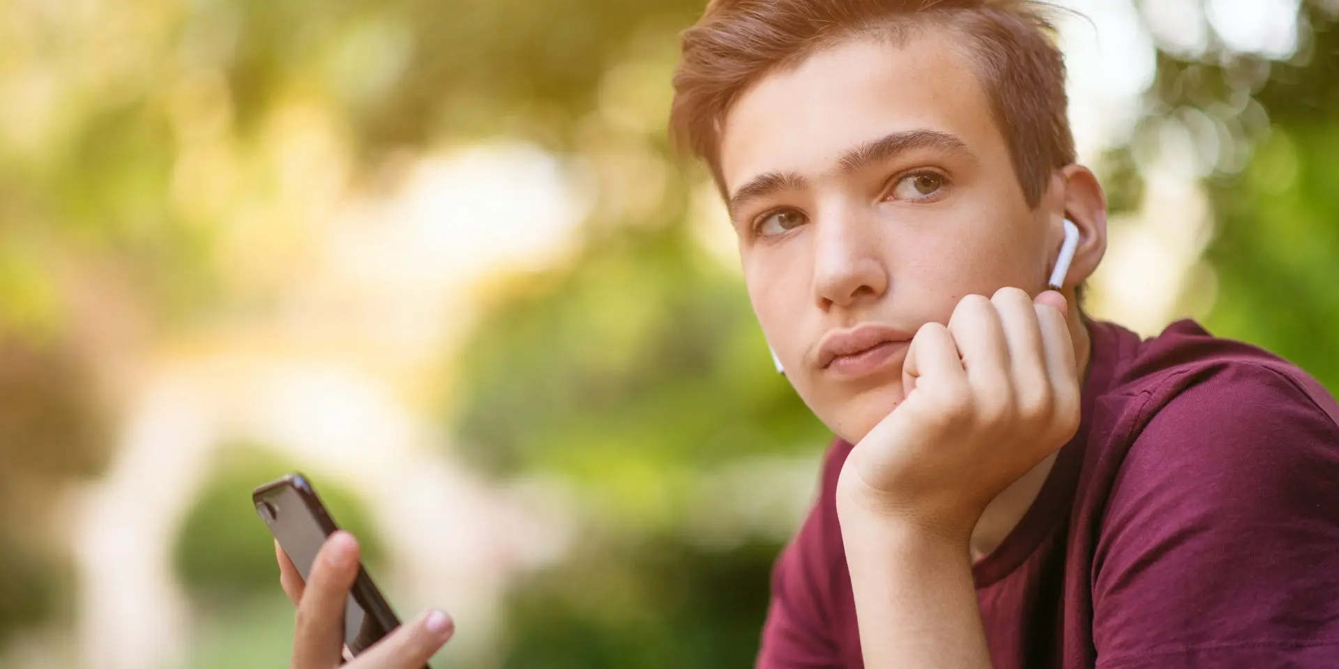 Teenage boy looking sad while listening to music