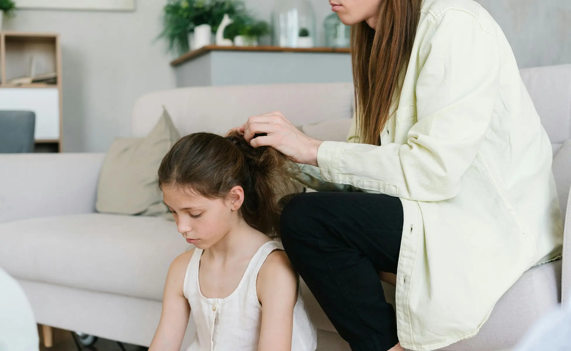 Small girl sat on the floor looking sad while her mum strokes her hair