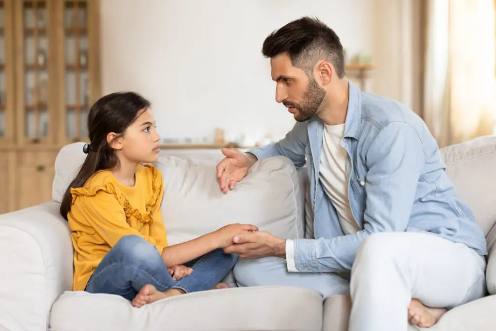 Man holding the hand of his daughter while they talk