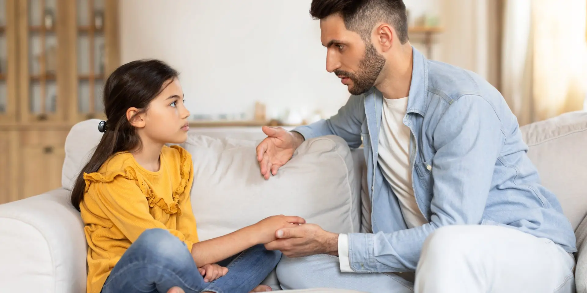 Man holding the hand of his daughter while they talk