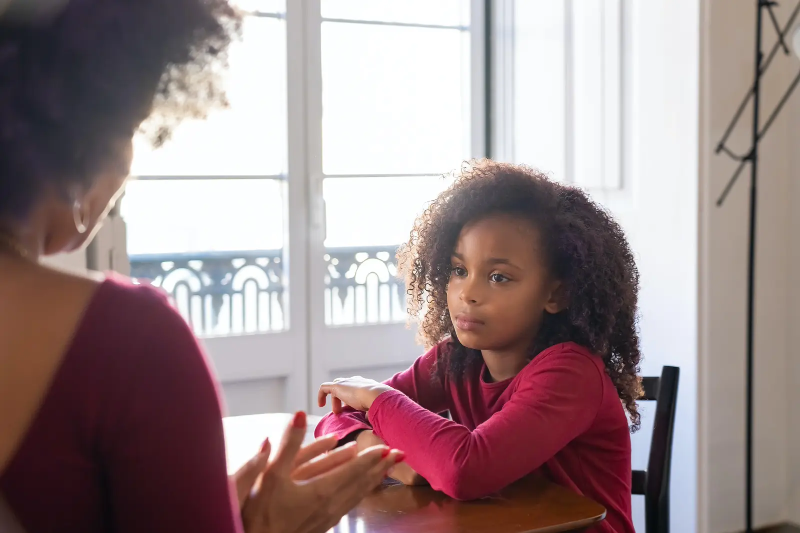 Telling a child someone has died: Header image featuring a young child looking to parent who is talking to them.
