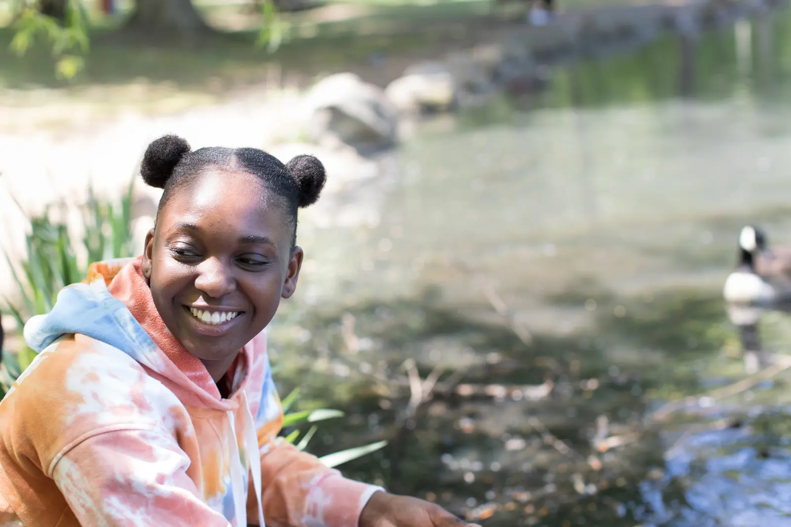 What to say (and not say) to a grieving teenager. Image of a black teenage girl smiling outside by a lake