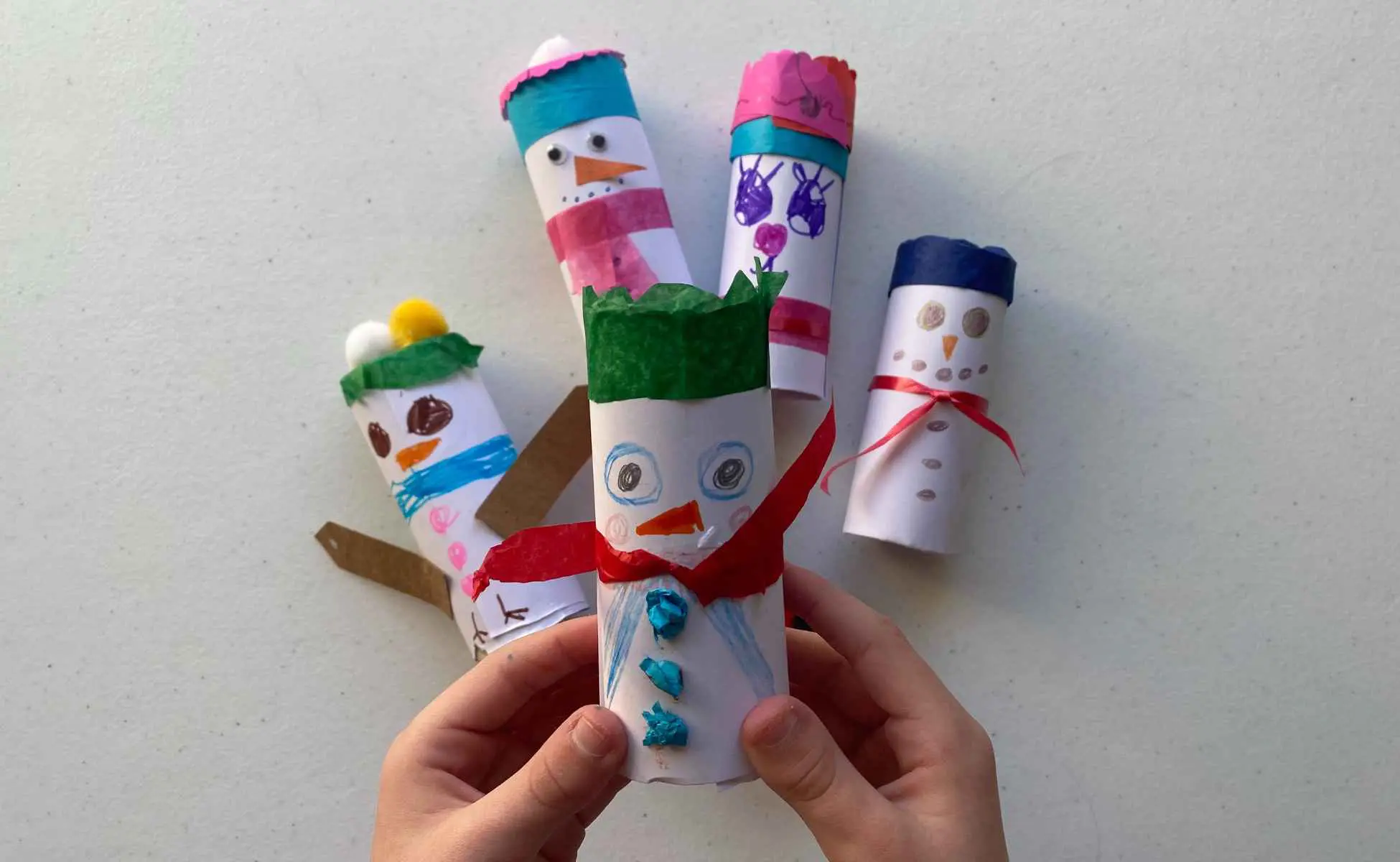 Snowman strike Christmas activity step 2 - Winston's Wish Child's hands holding a snowman made from a toilet roll tube. Step two of snowman strike Christmas activity