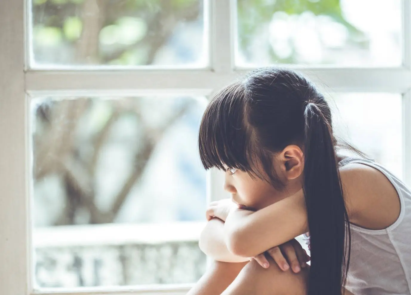 Photo of a young girl looking out of a window