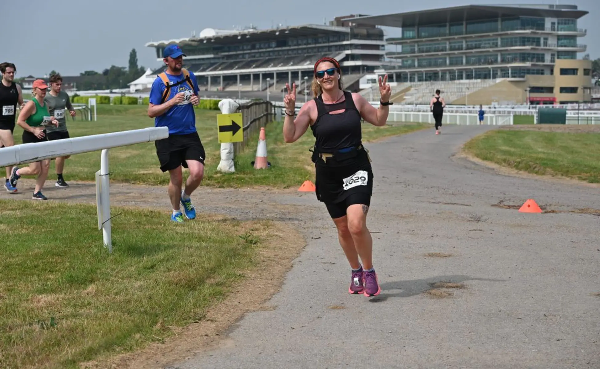 Cheltenham-running-festival-post-image Runner at the Cheltenham Running Festival giving peace signs as she runs