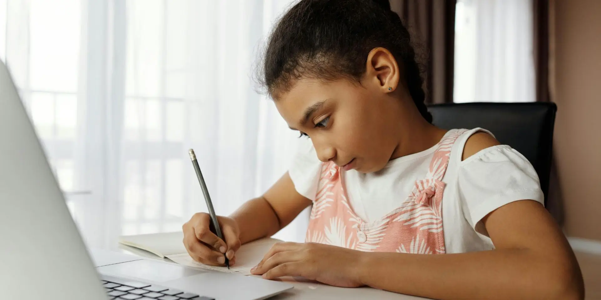 Small girl drawing in front of laptop