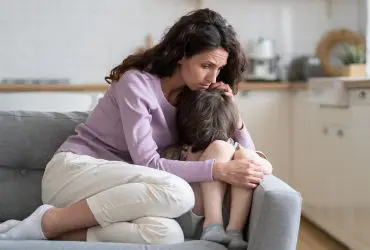 Explaining suicide to children and young people Woman comforting a small child on a sofa