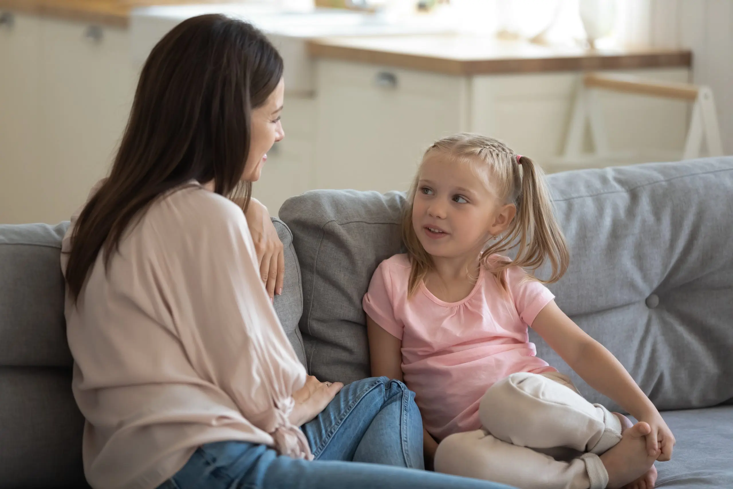 Adult and child having a conversation sitting on a sofa.