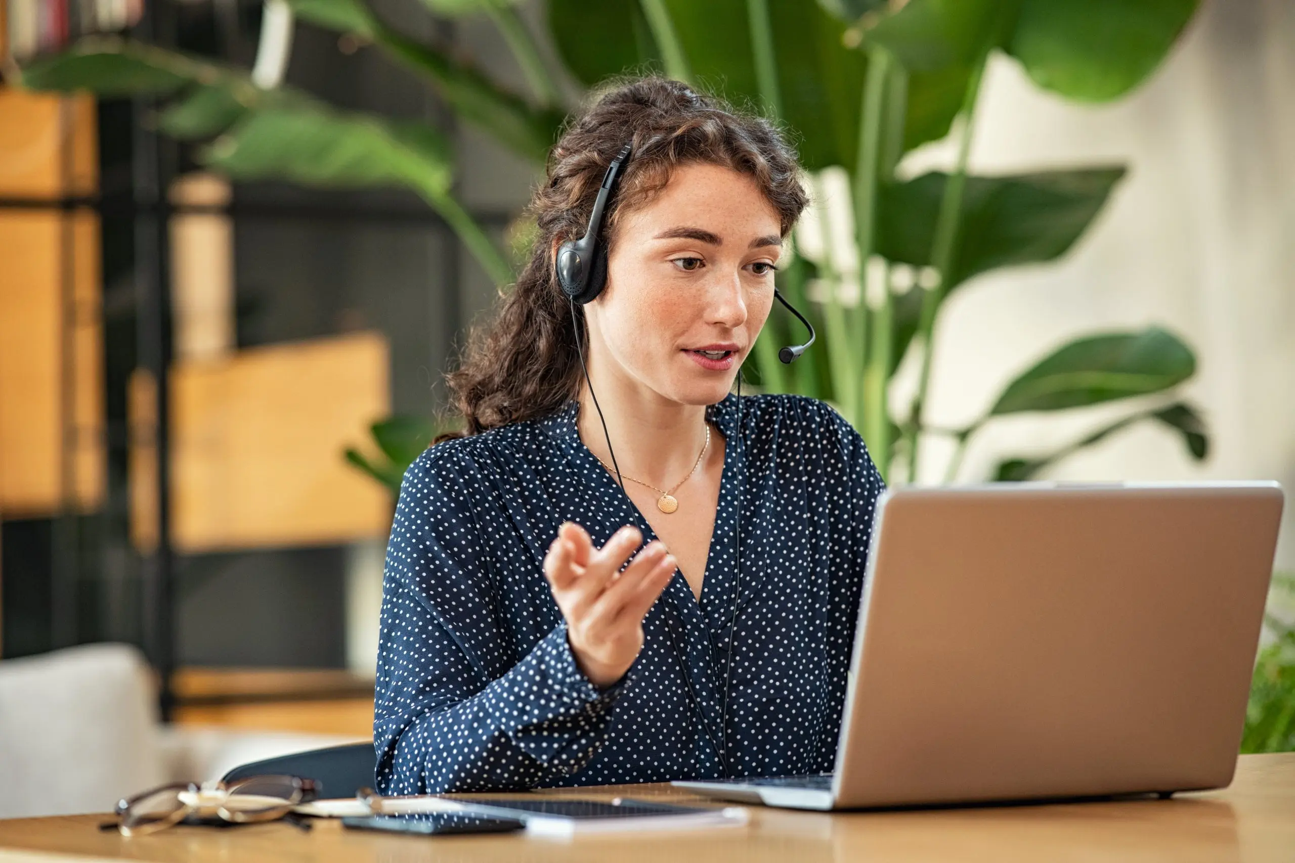 Woman sat at a desk in front of a laptop giving training
