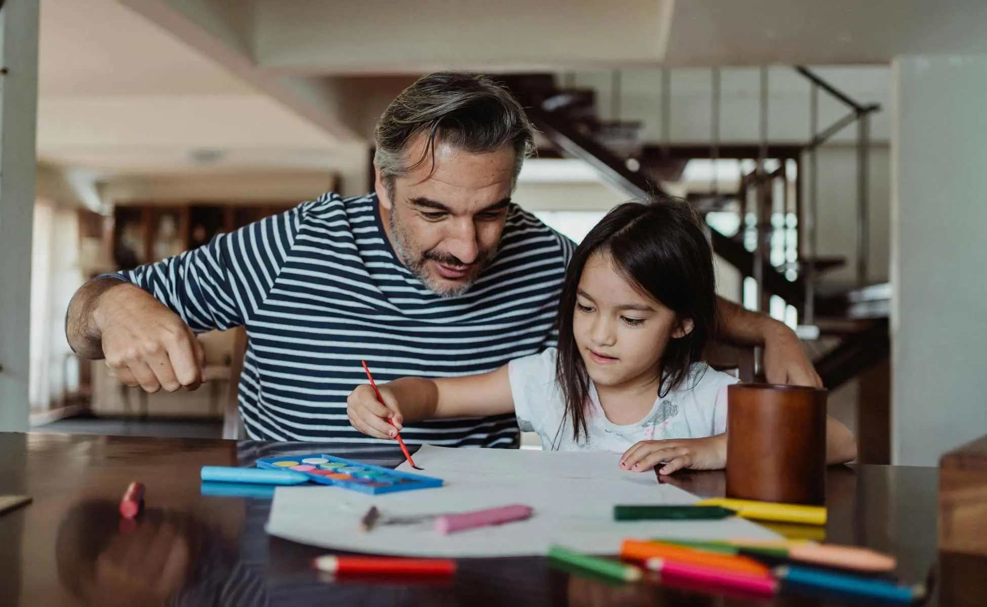 Dad and daughter sat at a table doing colouring - supporting neurodivergent grieving children