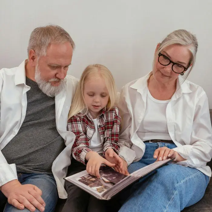 Supporting Children Bereaved of both Parents - Square (2) Grandparents sat with granddaughter, looking through a photo album