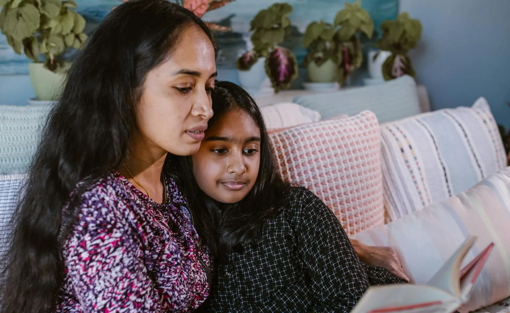 How to prepare a child for the death of a parent by cancer. Mum and daughter sat together on sofa reading from a booklet