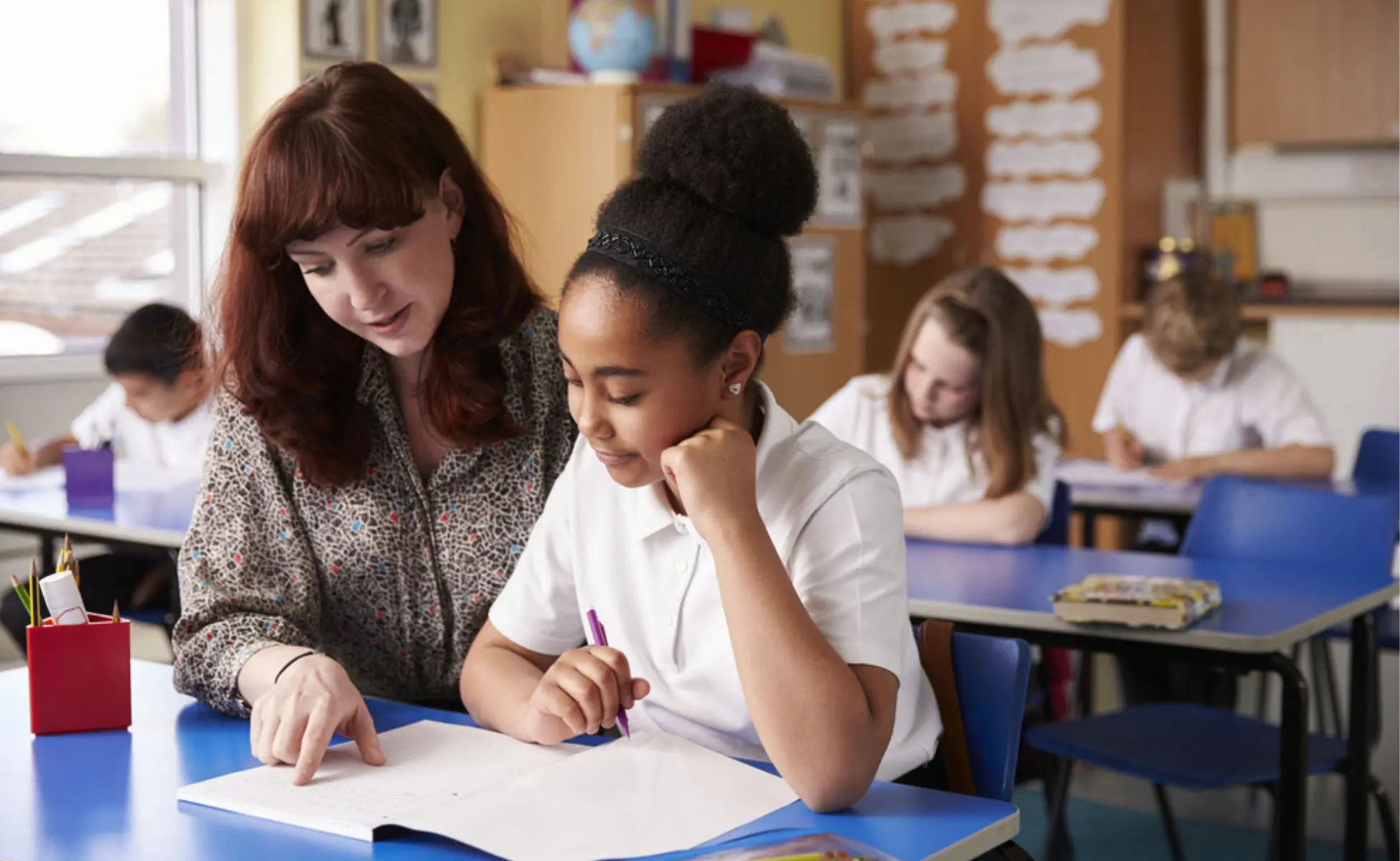 How schools and teachers can help a bereaved child return to school. Image of a teacher helping a student in a classroom