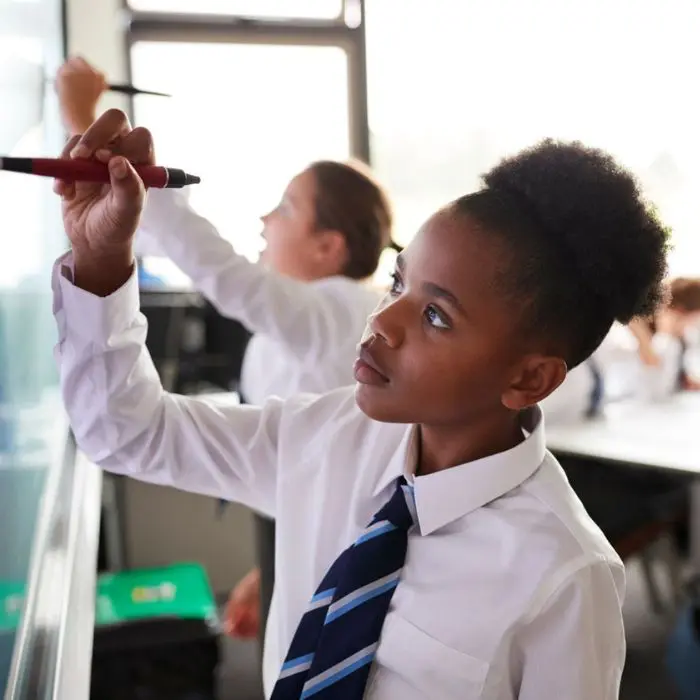 Supporting a child return to school How to support a child going back to school: image featuring a school child writing on a white board