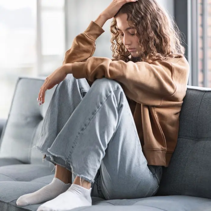 what not to say to a grieving yp What not to say to grieving young people. Teenage girl sat on the sofa looking sad and frustrated