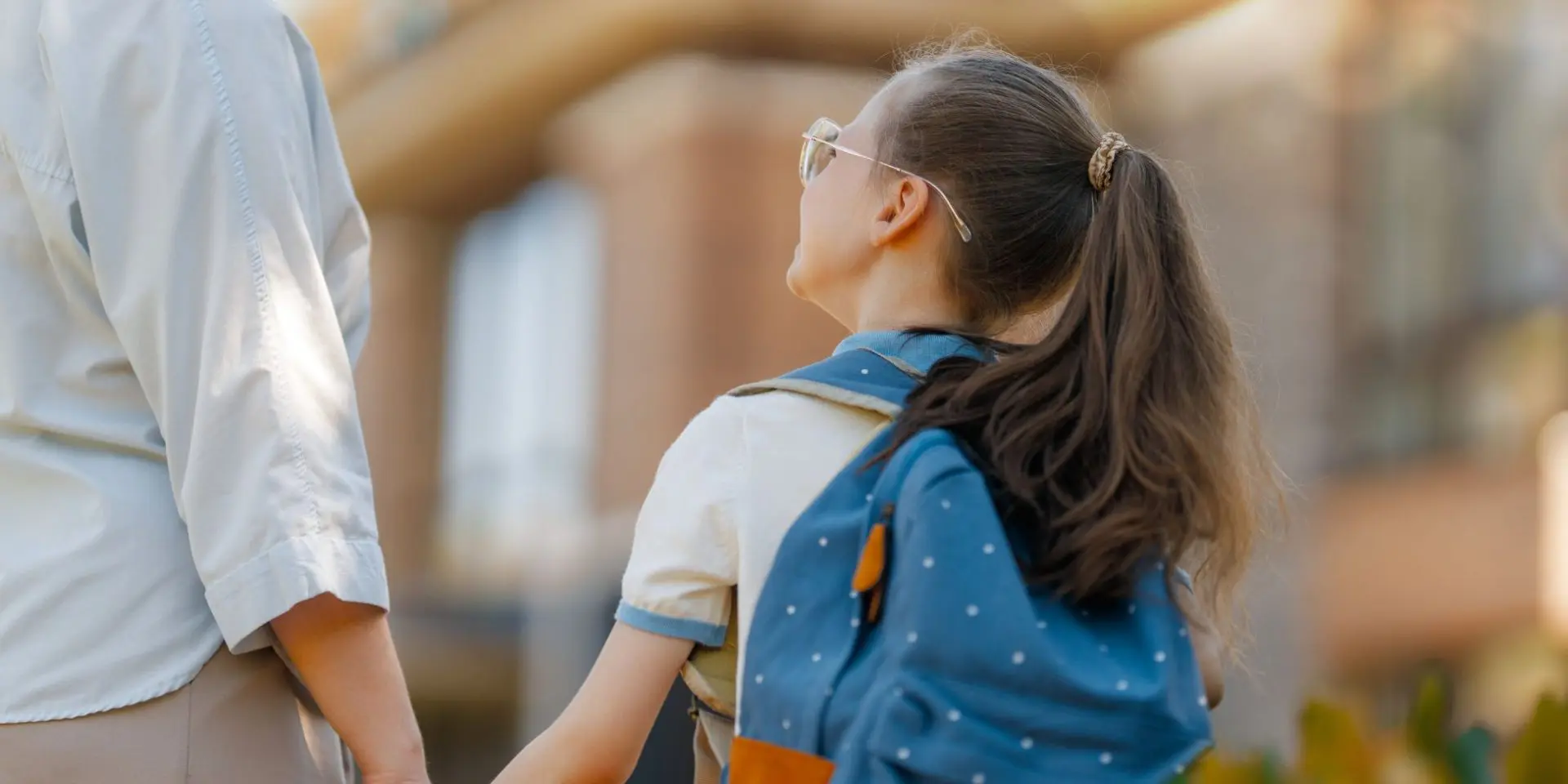 School child with backpack holding mum's hand