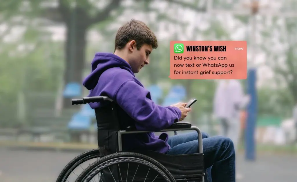 Teenage boy in a wheelchair using a phone.