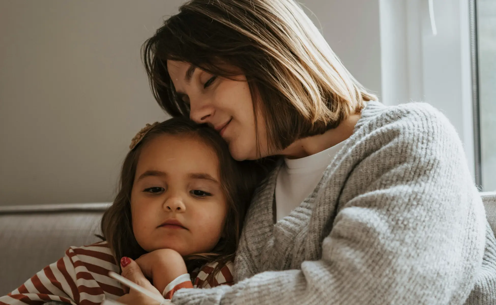 Parent sitting next to young child reading