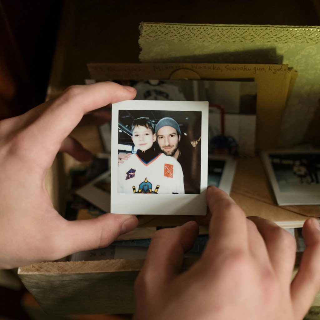 Hands holding a polaroid photo of a child with their dad