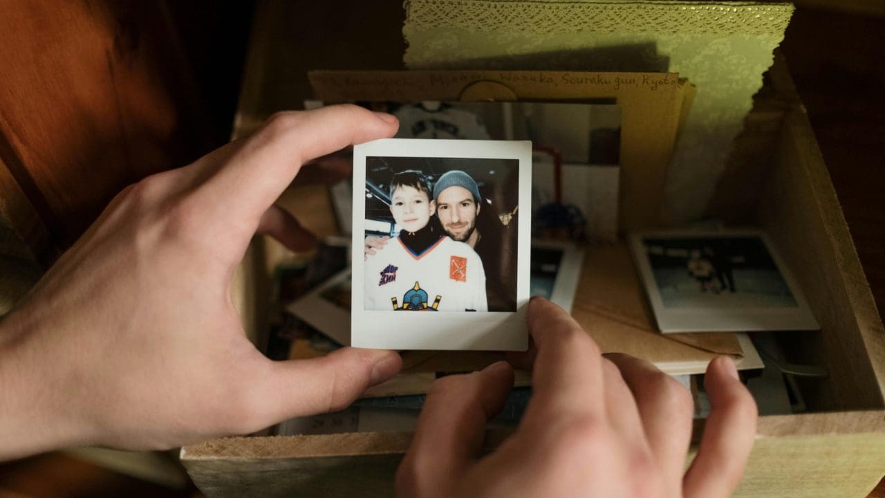 Hands holding a polaroid photo of a child with their dad