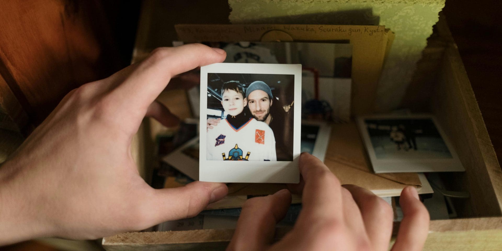 Hands holding a polaroid photo of a child with their dad