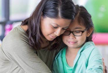 Young girl looking upset and being hugged by her mum - Supporting children after a baby dies - Winston's Wish
