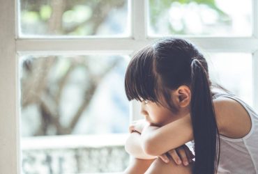 Photo of a young girl looking out of a window