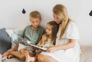 Mum sat reading a book with two children