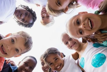 Young children in a circle looking down at the camera