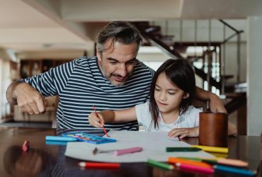 Dad and daughter sat at a table doing colouring - supporting neurodivergent grieving children
