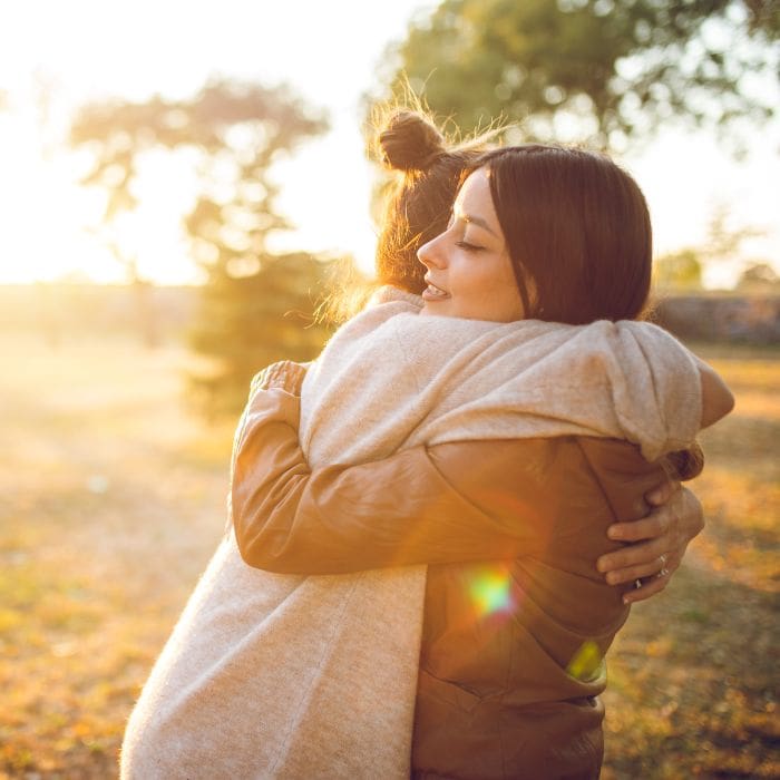 Two young women hugging one another outside