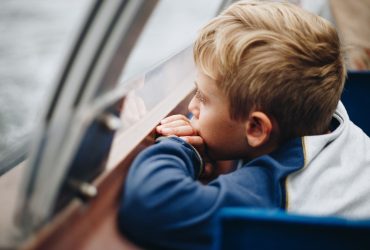 Are my children too young to know how their parent or sibling died: small boy with blonde hair looking out of the window