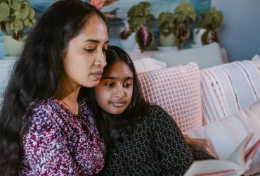 Prepare-death-cancer-replacement-2 How to prepare a child for the death of a parent by cancer. Mum and daughter sat together on sofa reading from a booklet