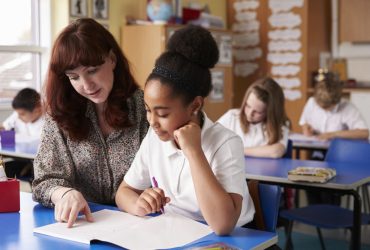 Returning to school - schools How schools and teachers can help a bereaved child return to school. Image of a teacher helping a student in a classroom