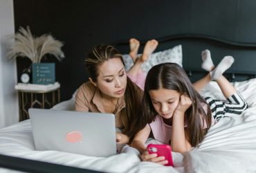 Supporting a grieving teenager: mum and daughter lying on bed while the daughter plays on her phone