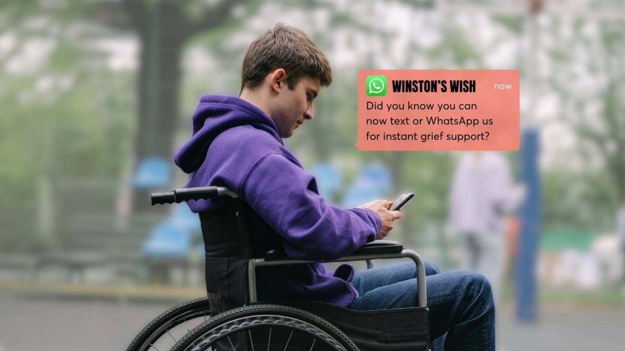Teenage boy in a wheelchair using a phone.
