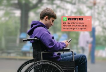 Teenage boy in a wheelchair using a phone.